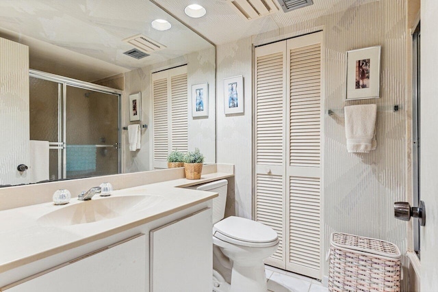 bathroom featuring tile patterned flooring, vanity, toilet, and a shower with door