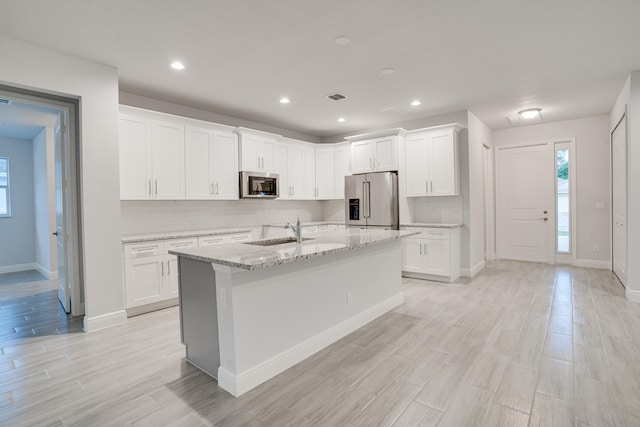 kitchen featuring light hardwood / wood-style floors, stainless steel appliances, a center island with sink, white cabinetry, and sink