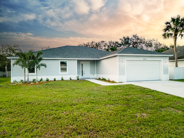 ranch-style home featuring a lawn and a garage