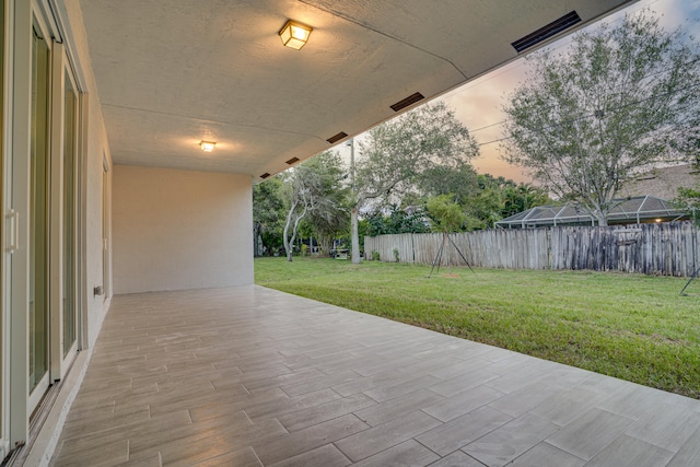 patio terrace at dusk featuring a yard