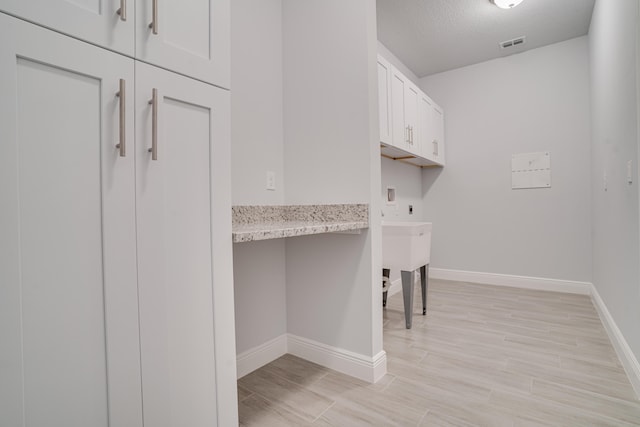 clothes washing area with washer hookup, a textured ceiling, hookup for an electric dryer, and cabinets