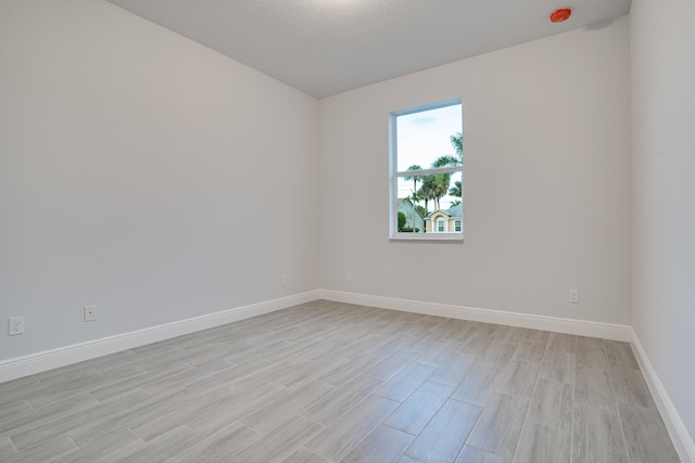 spare room with a textured ceiling and light wood-type flooring