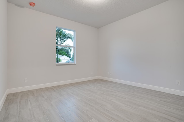 unfurnished room with a textured ceiling and light hardwood / wood-style floors