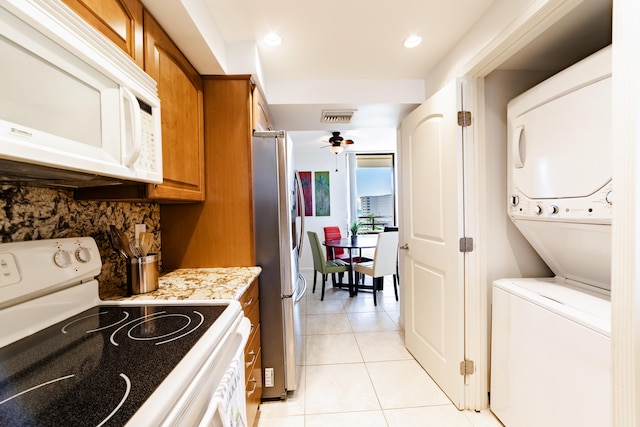 kitchen with white appliances, stacked washing maching and dryer, ceiling fan, and light tile flooring