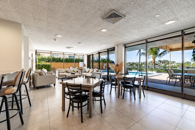 tiled dining space with floor to ceiling windows and a textured ceiling