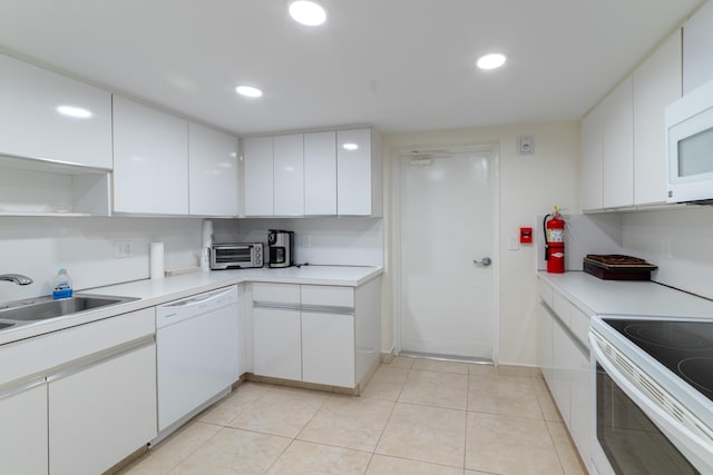 kitchen with white appliances, sink, white cabinetry, and light tile floors