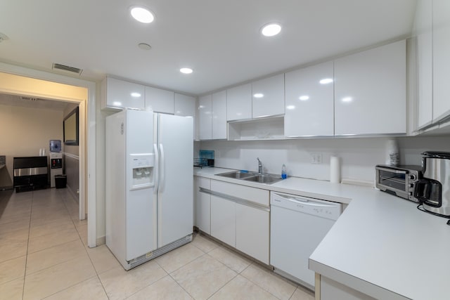 kitchen featuring white appliances, white cabinetry, light tile floors, and sink