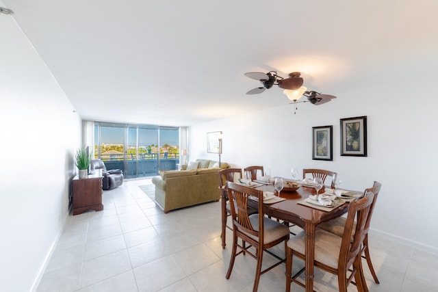 dining space featuring a wall of windows, light tile floors, and ceiling fan