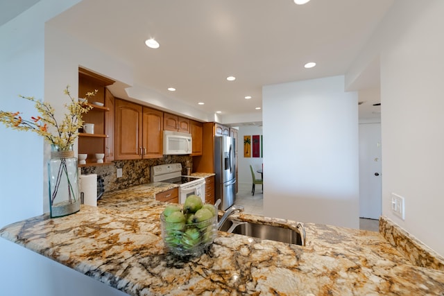 kitchen with light tile flooring, light stone countertops, tasteful backsplash, white appliances, and sink