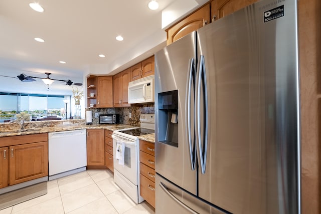 kitchen featuring white appliances, sink, light tile floors, light stone counters, and tasteful backsplash