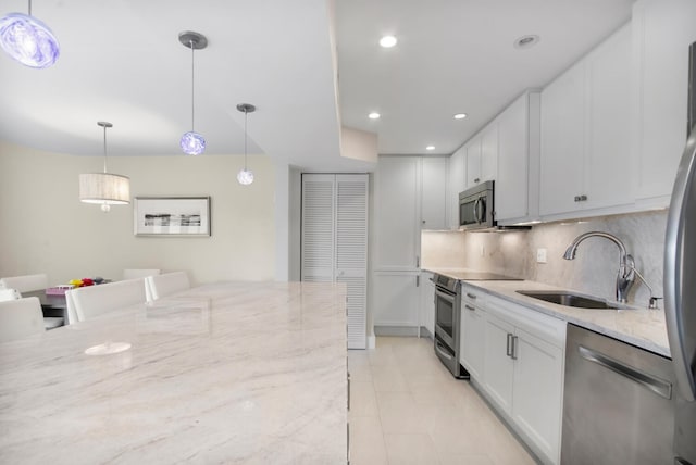 kitchen with light stone counters, pendant lighting, appliances with stainless steel finishes, and white cabinetry