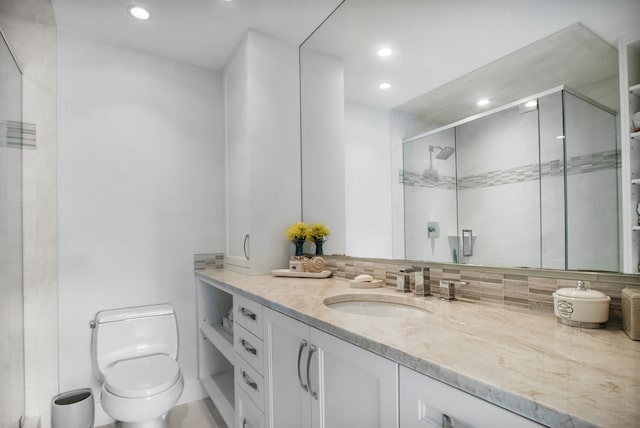 bathroom with toilet, a shower with door, vanity, and tasteful backsplash