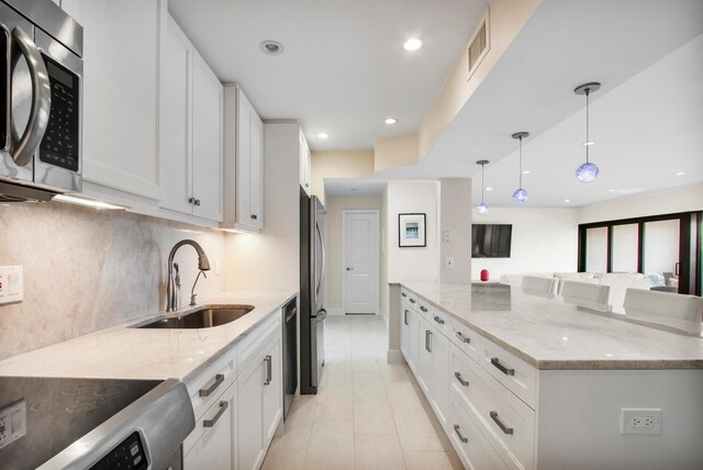 kitchen with light stone counters, sink, stainless steel appliances, and white cabinets