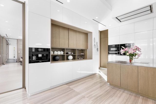 kitchen with white cabinets, light hardwood / wood-style floors, light brown cabinets, and double oven