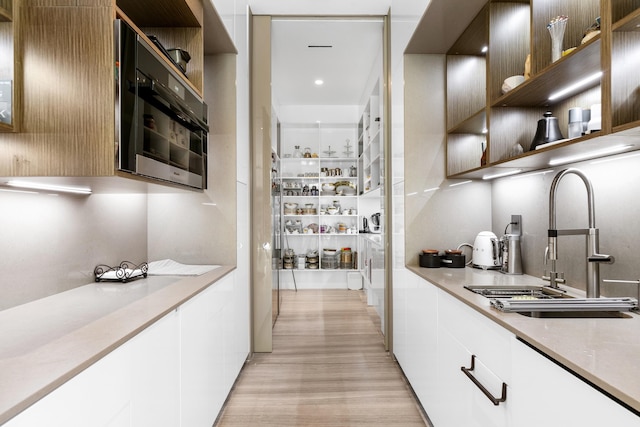 kitchen featuring white cabinets, light wood-type flooring, and sink