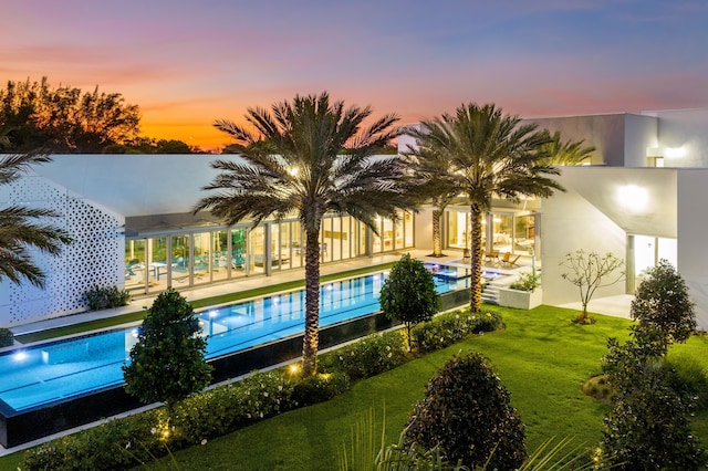 pool at dusk with a lawn and a patio area