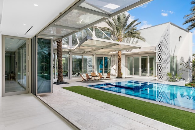 rear view of house with a swimming pool with hot tub, a patio, and glass enclosure