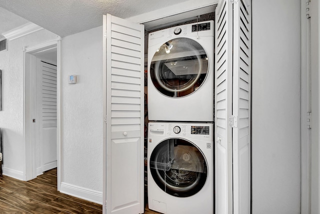 laundry room featuring a textured ceiling, dark wood-type flooring, and stacked washer and dryer