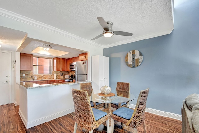 dining space featuring dark wood-type flooring, ornamental molding, ceiling fan, and a textured ceiling