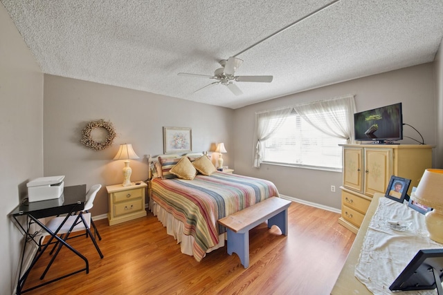 bedroom featuring light hardwood / wood-style floors, ceiling fan, and a textured ceiling