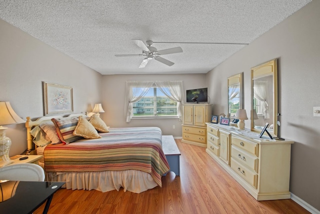 bedroom with ceiling fan, a textured ceiling, and light hardwood / wood-style floors