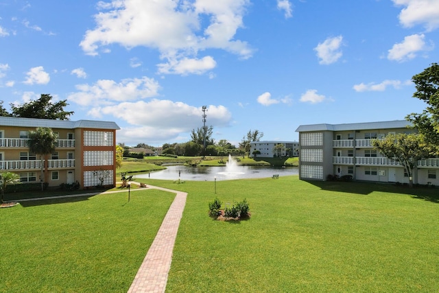 view of home's community with a water view and a lawn