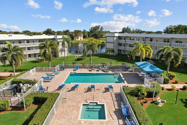 view of pool featuring a water view, a lawn, and a patio area