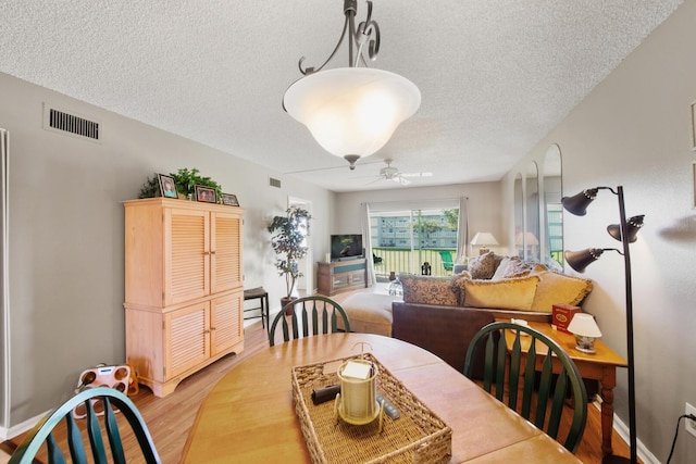 dining space with light hardwood / wood-style floors, ceiling fan, and a textured ceiling