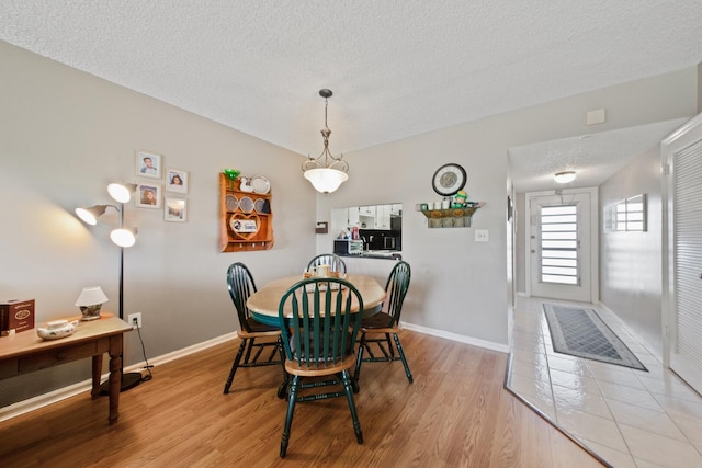 dining room with a textured ceiling and light hardwood / wood-style flooring