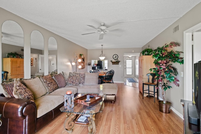 living room with a textured ceiling, light hardwood / wood-style floors, and ceiling fan