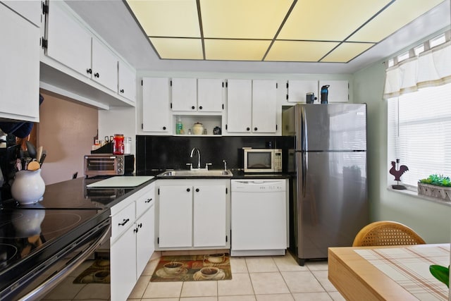 kitchen with tasteful backsplash, white cabinets, appliances with stainless steel finishes, and sink