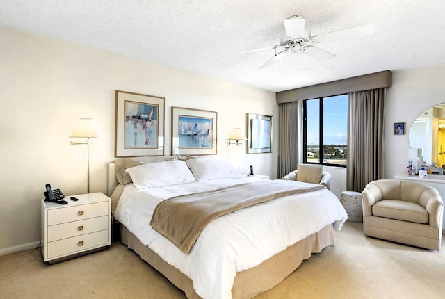 bedroom featuring a textured ceiling, light colored carpet, and ceiling fan