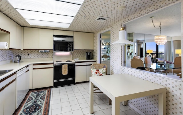 kitchen with white appliances, light tile patterned floors, decorative light fixtures, an inviting chandelier, and cream cabinetry