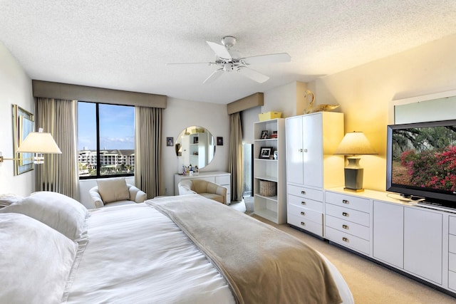 bedroom featuring ceiling fan, light colored carpet, and a textured ceiling