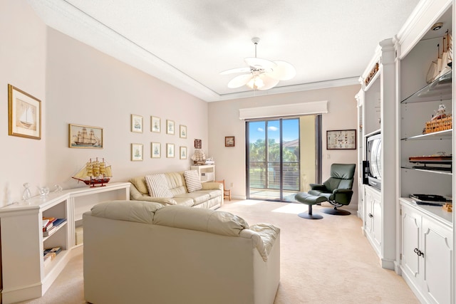 carpeted living room featuring ceiling fan, ornamental molding, and a textured ceiling