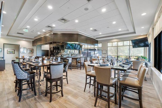 dining area with a tray ceiling and light hardwood / wood-style flooring