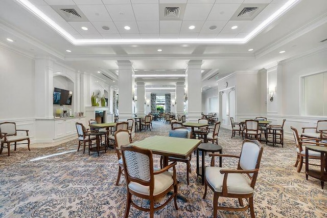 dining space featuring carpet, a raised ceiling, ornamental molding, and ornate columns