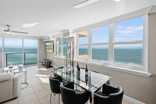 tiled dining room featuring ornamental molding, ceiling fan, and a water view