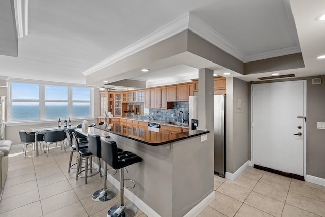 kitchen featuring backsplash, a kitchen bar, stainless steel fridge with ice dispenser, sink, and a water view