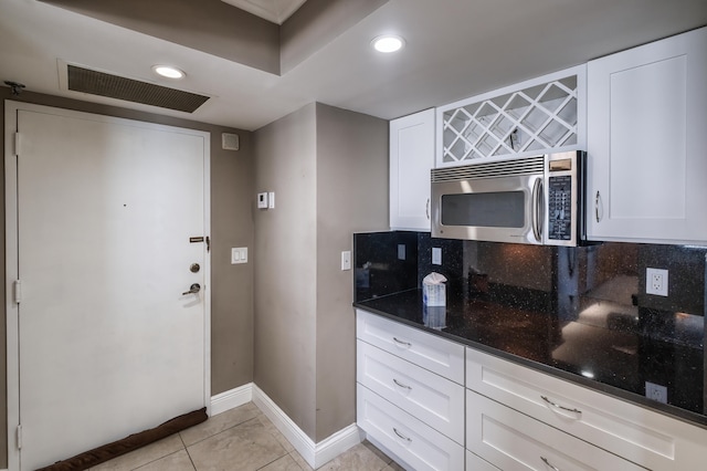 kitchen with dark stone counters, light tile flooring, tasteful backsplash, and white cabinetry