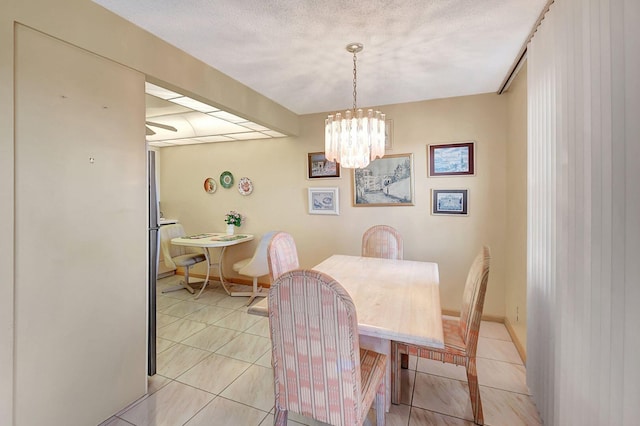 tiled dining room with a chandelier and a textured ceiling