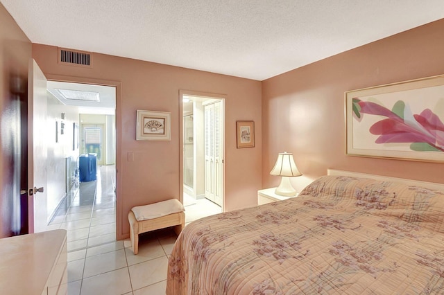 tiled bedroom featuring connected bathroom and a textured ceiling