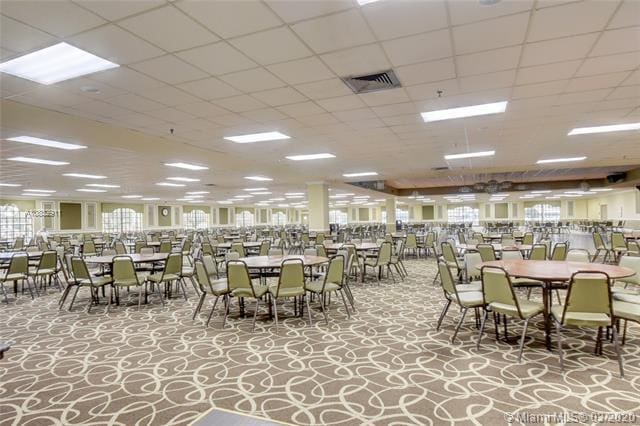 carpeted dining area with a paneled ceiling