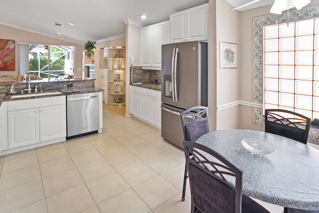 kitchen featuring appliances with stainless steel finishes, ornamental molding, vaulted ceiling, sink, and white cabinetry