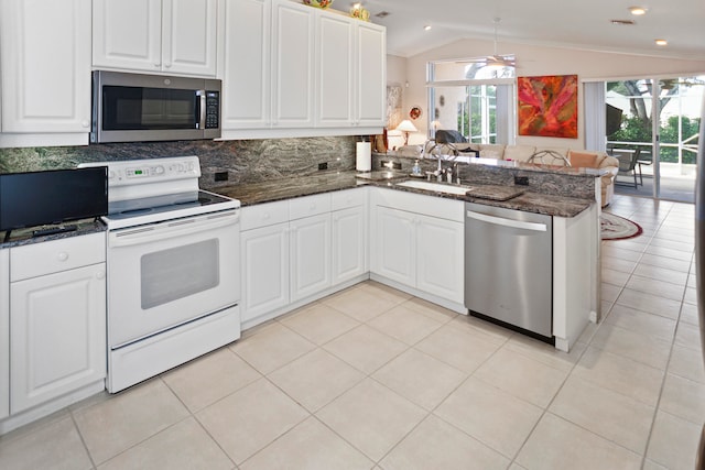 kitchen featuring white cabinets, sink, vaulted ceiling, appliances with stainless steel finishes, and kitchen peninsula