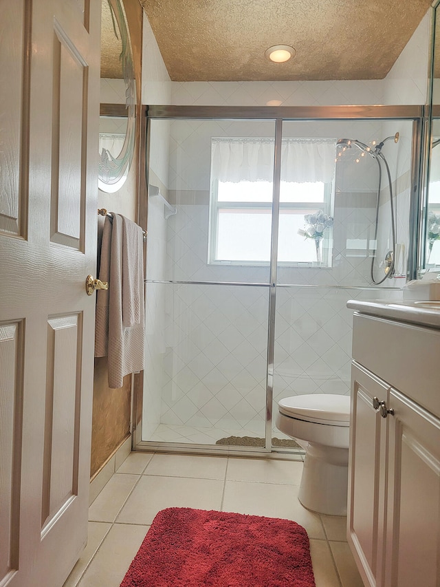 bathroom with tile patterned flooring, vanity, a shower with door, and a textured ceiling