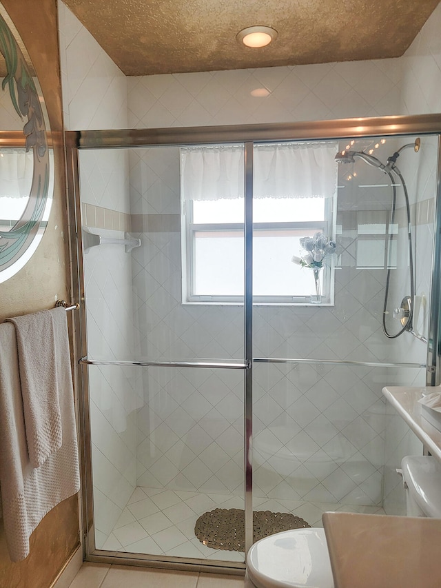 bathroom featuring a shower with door, tile patterned flooring, and toilet