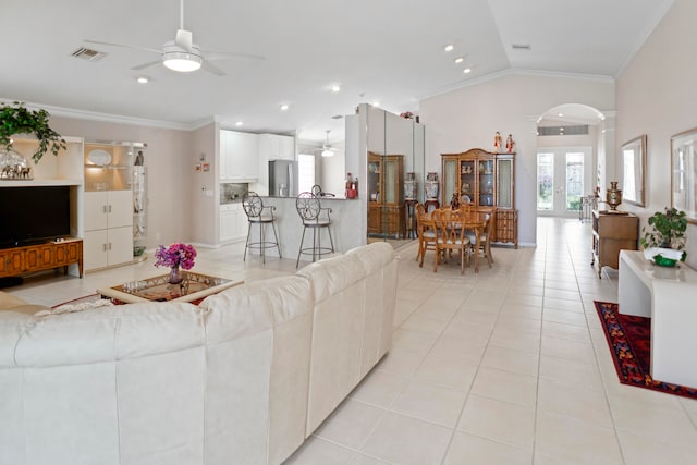 living room featuring vaulted ceiling, light tile patterned floors, crown molding, and french doors