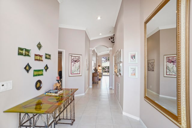 corridor featuring light tile patterned floors, crown molding, and a towering ceiling