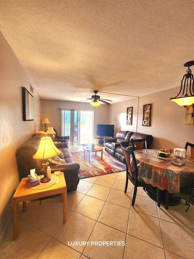 tiled living room with a textured ceiling and ceiling fan